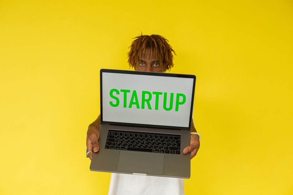 Mladi profesionalac s laptopom na kojem je prikazan naziv 'Startup'