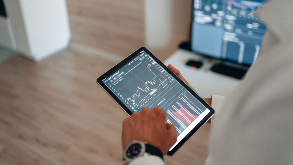 Blizu snimka ruku koje koriste tablet za online trgovanje i tržišnu analizu.